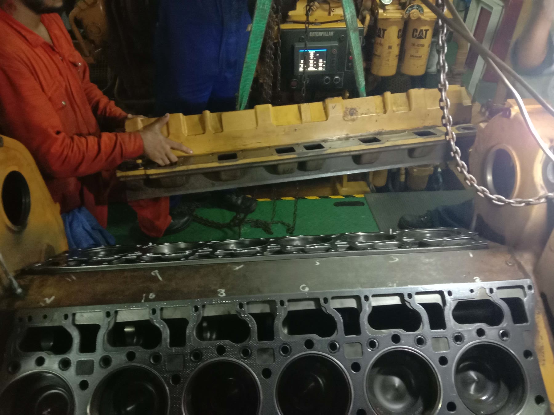 Diesel cylinder head being handled by workshop technicians