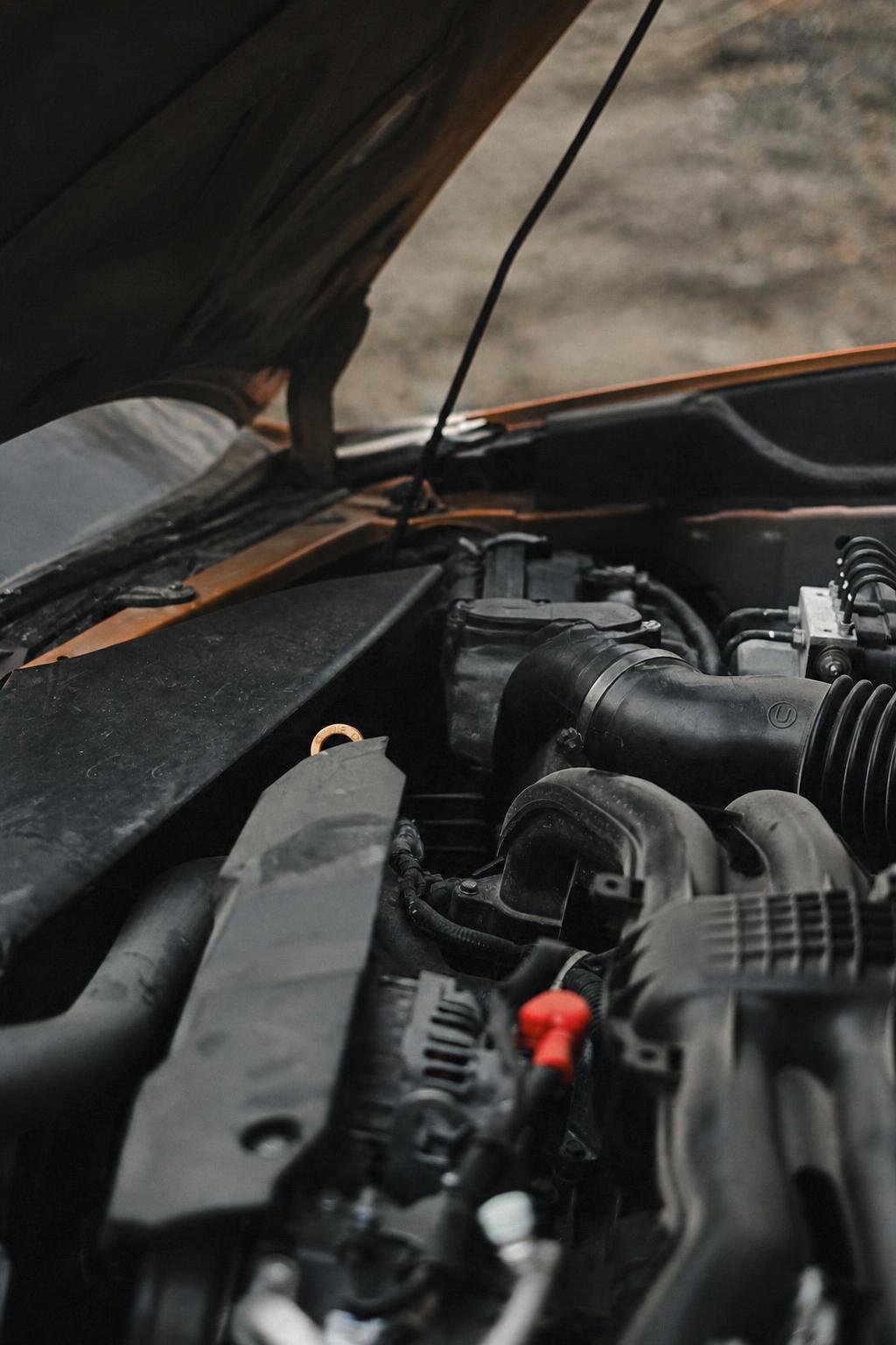 Tight close-up of a technician's hands inspecting components inside an engine bay.