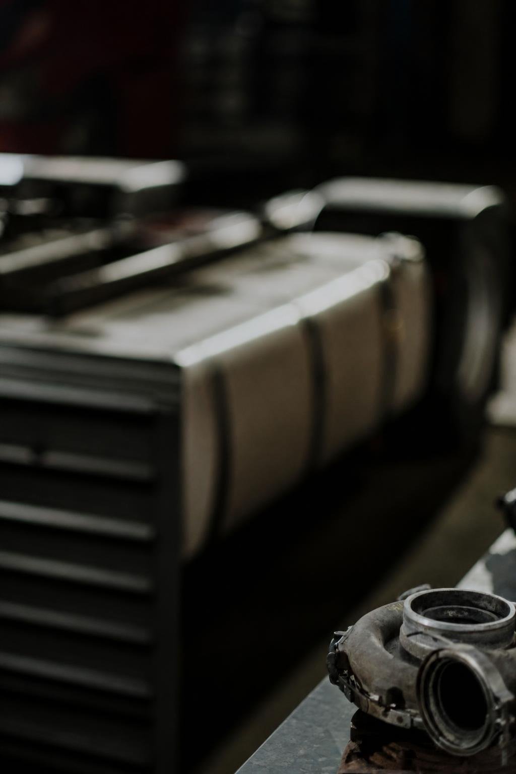 A focused workshop portrait of a technician inspecting a weathered turbocharger component at the bench.