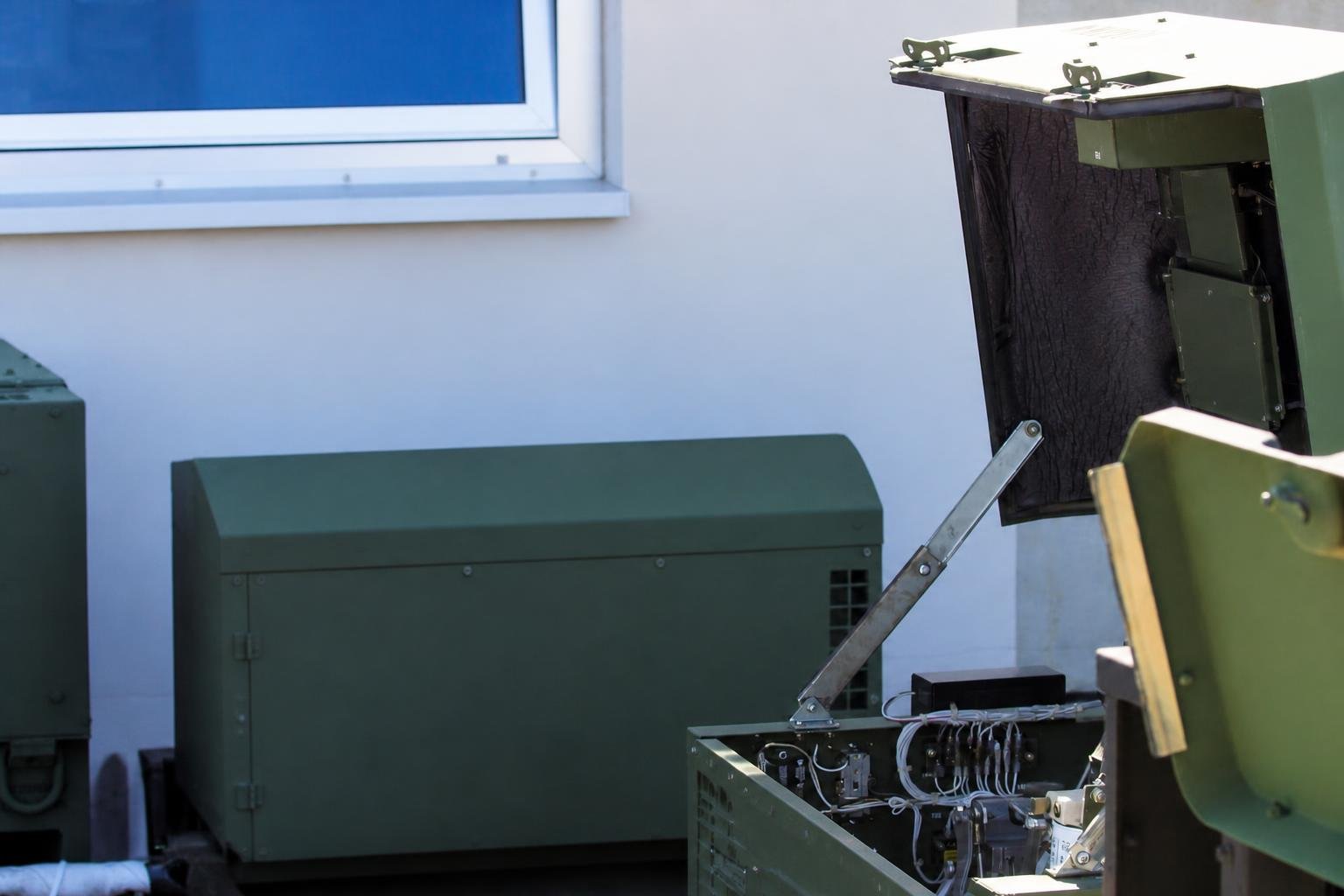 Two technical specialists examine a diesel generator and discuss completed maintenance.