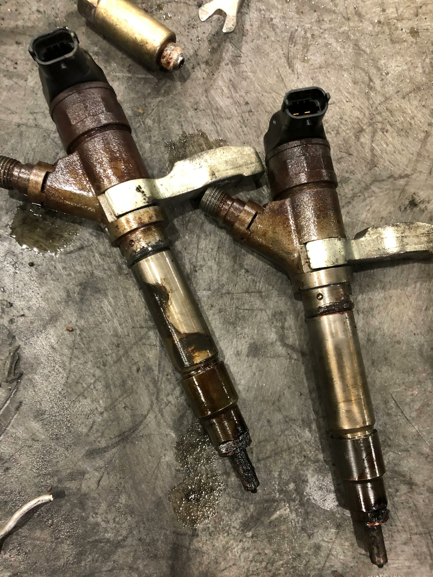 three used common-rail injectors laid on shop floor